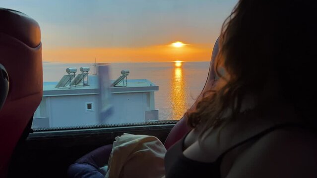 a girl with fluffy hair looks into the distance in a bus and looks at the sunset beautiful views travel by bus teenagers sky. nature