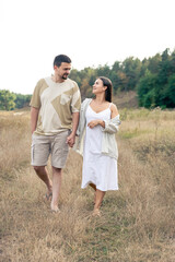 A man and a woman are walking in a field, a happy couple.