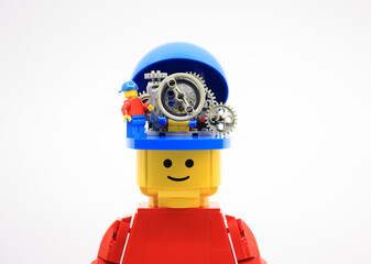 Naklejka premium Hong Kong - September 2 2023: small worker fix the gear wheels in the head of giant man