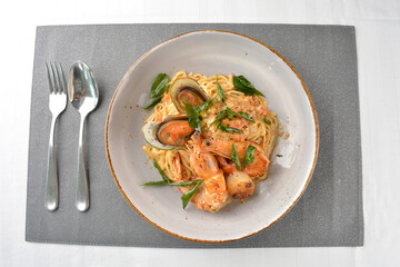 seafood pasta with big tiger prawn, scallop shell clam and muscle in olive oil salted egg yolk paste sauce in plate on white marble table western spaghetti cuisine halal food hotel luxury cafe  menu