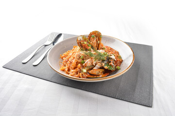 seafood pasta with big tiger prawn, scallop shell clam and muscle in spicy chilli crab tomato paste sauce in plate on white marble table western spaghetti cuisine halal food hotel luxury cafe menu