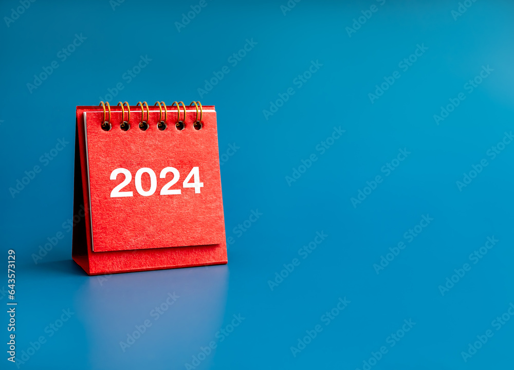 Wall mural Happy new year 2024 banner background. 2024 white numbers year on red small desk calendar cover standing on blue background with copy space. Business goals plan and success schedule concepts.