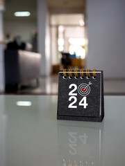 Happy new year 2024 banner background. 2024 numbers year with target icon on black small desk...