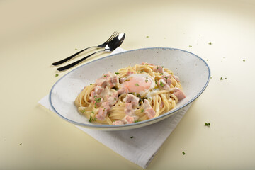 stir fried carbonara pasta noodle with chicken ham and half boiled egg in creamy cheese white milk sauce in plate on white table western vegetarian spaghetti cuisine halal food hotel luxury cafe menu