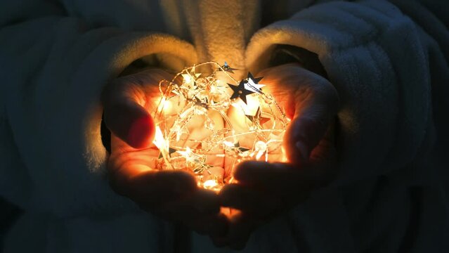 lose up of woman hands holding and protection bulb stars light in the dark. Hope and romantic concept. Daydreamer day dreaming people lifestyle. Holiday christmas new year decoration. Future life