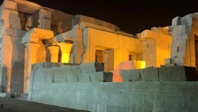 Kom Ombu temple illuminated at night view from the side.  Beautiful warm lighting just beyond the wall. On the Nile river, Egypt.
