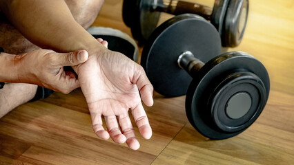 Male athlete massaging his wrist and hand suffering from wrist pain caused by sprain or joint...