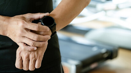 Sport man checking workout result on smartwatch app after exercise session in fitness gym. Wearable device or personal fitness tracker. Smart watch technology for health tracking and physical activity
