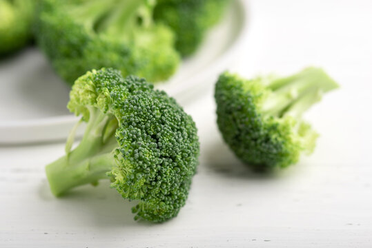 Fresh green broccoli on a plate on a white wooden background.