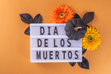 Dia de los muertos Feast flat lay, Mexican Day of the Dead holiday background with fall black, orange, yellow flowers, lightbox with text Dia de los muertos, colorful painted skull