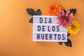 Dia de los muertos Feast flat lay, Mexican Day of the Dead holiday background with fall black, orange, yellow flowers, lightbox with text Dia de los muertos, colorful painted skull