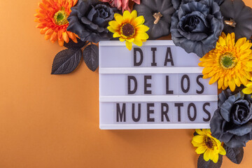 Dia de los muertos Feast flat lay, Mexican Day of the Dead holiday background with fall black, orange, yellow flowers, lightbox with text Dia de los muertos, colorful painted skull