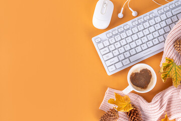 Autumn holidays cozy background, cozy flat lay with coffee latte cup with heart decor, computer laptop keyboard, earphones, warm sweater or plaid, fall leaves, on beige background top view copy space 