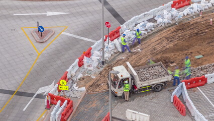 Process of sidewalk road repairing with many builder workers and equipment aerial timelapse in Dubai