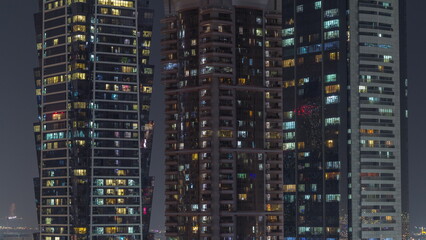 Tall blocks of flats with glowing windows located in residential district of city aerial timelapse.