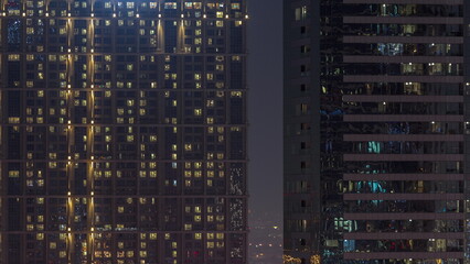 Tall blocks of flats with glowing windows located in residential district of city aerial timelapse.