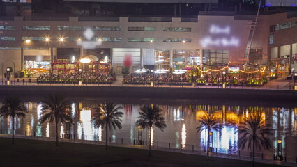 Obraz premium Walking promenade along water canal in Business Bay district of Dubai aerial night timelapse.