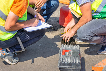 Road engineers measure the thickness of the laid asphalt and record the data in a spreadsheet.