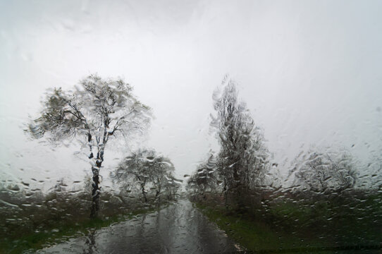 Vista oto&ntilde;al de la carretera con lluvia desde el interior de un veh&iacute;culo con agua en el parabrisas.