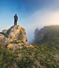 woman stands on a rock above a river canyon. female tourist enjoys foggy autumn landscape. nature of Ukraine