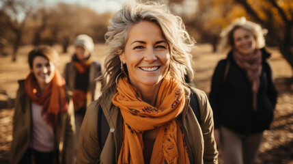 Portrait of smiling senior woman with group of friends walking in autumn park.