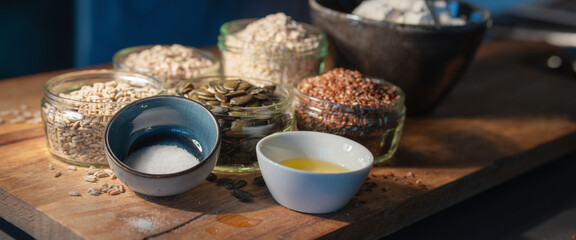 Cereals grains and pumpkin seeds portioned in glasses on rustic wooden board for a bread preparation. Healthy groceries background. - obrazy, fototapety, plakaty