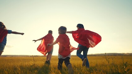 team of kids superheroes run. happy family kid concept. a group of children playing superheroes in capes and masks run through the grass at sunset. success business striving for goal dream concept © ibragimova