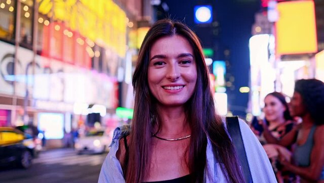 Portrait of beautiful attractive Caucasian happy woman smiling and looking at camera standing on Times Square in the USA. Pretty joyful adult girl enjoying traveling. Tourism concept.
