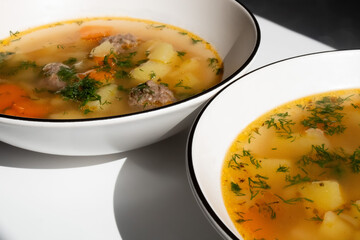 homemade soup with potatoes, meatballs, parsley in a white plate