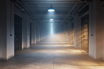A dark corridor of jail with light shining through small windows in misty cells