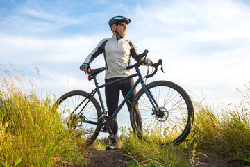 Bearded male cyclist is resting with a bike on the road in nature. cycling and health hobbies