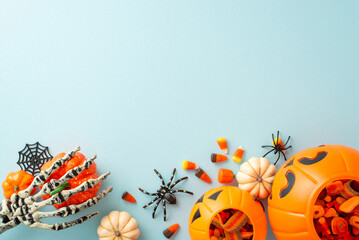 Festive trick or treat tradition for kids. Overhead shot displaying a pumpkin basket with candies and Halloween decorations on blue isolated background, suitable for text or ad placement - obrazy, fototapety, plakaty