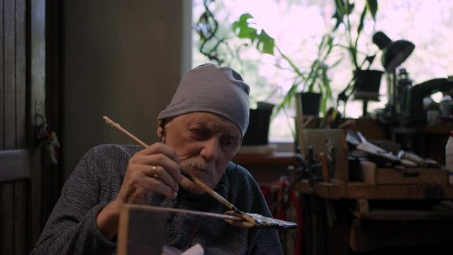 Elderly male master works in his workshop restoring japanese deba knife sheath