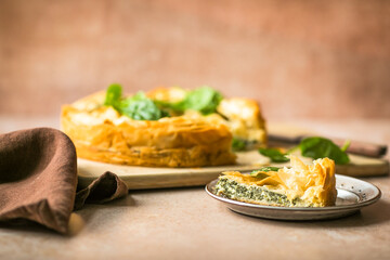 Spanakopita Greek Pie with Spinach and Cheese on wooden board. Dark background. Top view