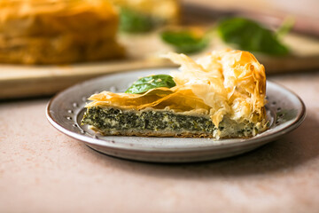 Spanakopita Greek Pie with Spinach and Cheese on wooden board. Dark background. Top view