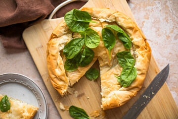 Spanakopita Greek Pie with Spinach and Cheese on wooden board. Dark background. Top view