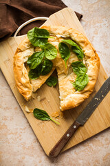 Spanakopita Greek Pie with Spinach and Cheese on wooden board. Dark background. Top view