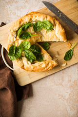 Spanakopita Greek Pie with Spinach and Cheese on wooden board. Dark background. Top view