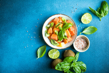 Salad with  ripe papaya fruit, kiwi lime and salt on a color background. Appetizing tropical fruit
