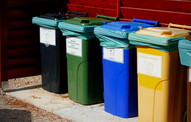 Five colorful recycle plastic bins with description in wooden shelter on the street of Croatia....