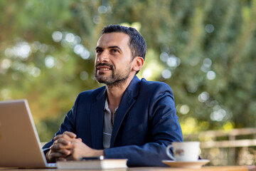 a mature business man in an outdoor ambition working ,blue coat suit,multiracial armenian, biting the lips