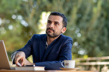 a mature business man in an outdoor ambition working ,blue coat suit,multiracial armenian,serous working looking coworkers