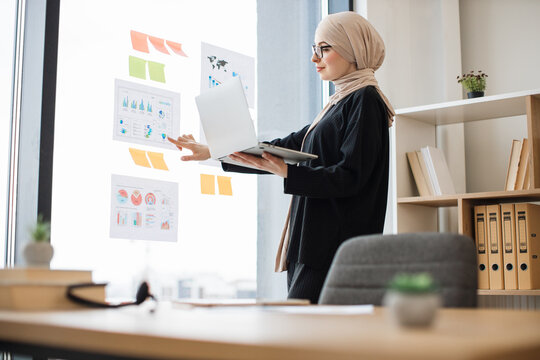 Expert analyzing report with charts using laptop at work - Powered by Adobe