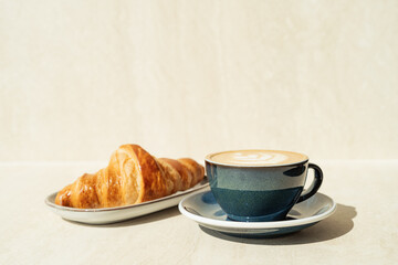 Still life shot of coffee and croissant at sunny morning