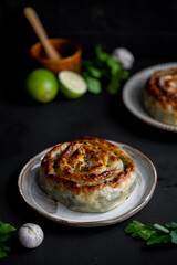 Traditional Turkish Rolled Borek Tepsi Böreği with feta cheese and spinach on a dark background. Filo pastry.