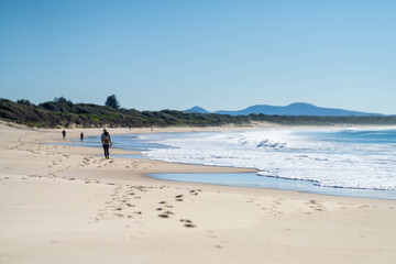 couple walking on the beach, women in coats and beanies walk down a winter beach in hobart tasmania, australia.
