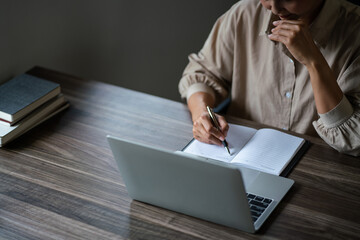 Female entrepreneur working to analysis strategy of startup project and writing ideas down notebook