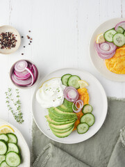 Coloruful healthy and fresh dinner or lunch with avocado, cucumber salad, red onion and omelet. Dressing with yogurt sauce, thyme, lemon and black pepper.