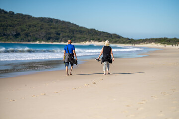 couple walking on the beach, women in coats and beanies walk down a winter beach in hobart...