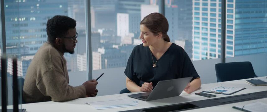 Businesspeople in Skyscraper Office: Business Meeting of Two Managers Using Laptop. Female CEO and African American Operations Director Succesfully Complete a Task And Fist Bump. Anamorphic Shot